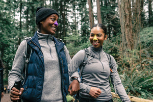 two black woman walking in woods wearing sunscreen on nose